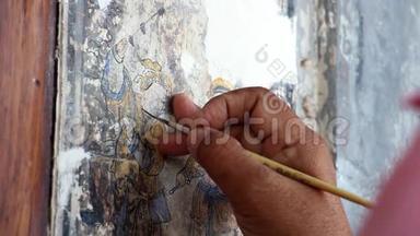 一位绘画艺术家的手在修理一幅中国画。 旧建筑墙体国画改造..